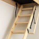 A wooden loft ladder partially extended towards the ceiling, demonstrating installation process.