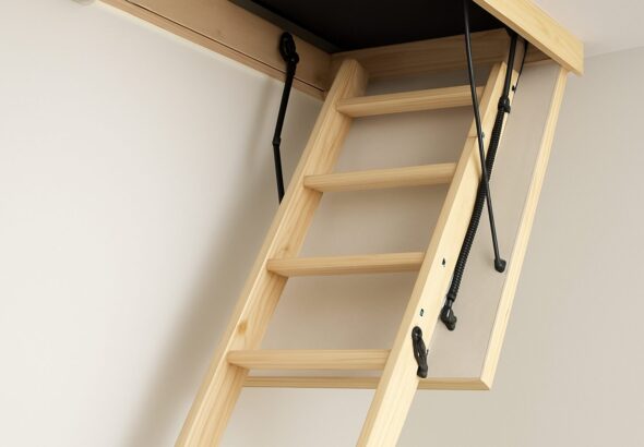 A wooden loft ladder partially extended towards the ceiling, demonstrating installation process.